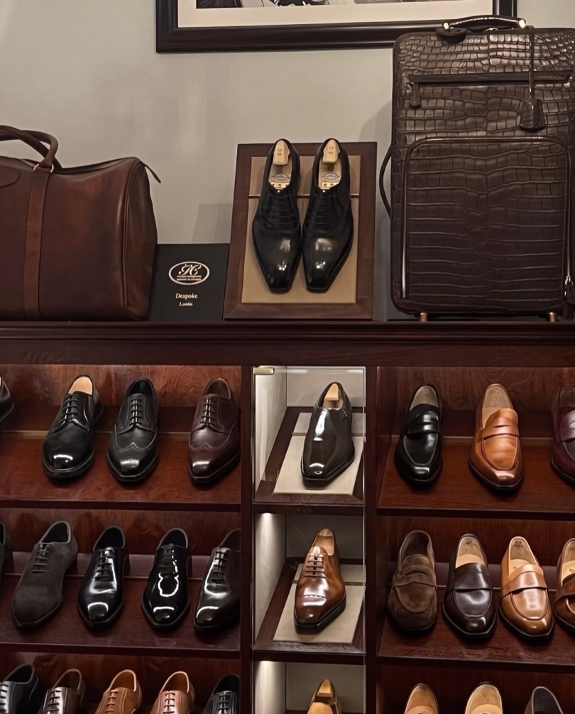 A considered dressing room of polished leather shoes in rows, with leather holdalls and a crocodile case.